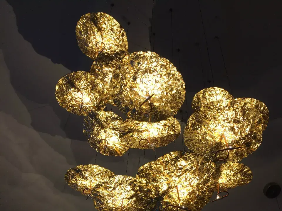 Zoom sur un magnifique plafonnier garni de coupoles suspendues de couleur doree créant des effets de lumieres sur le plafond / decoration par ViolaDeco, Iana Viola